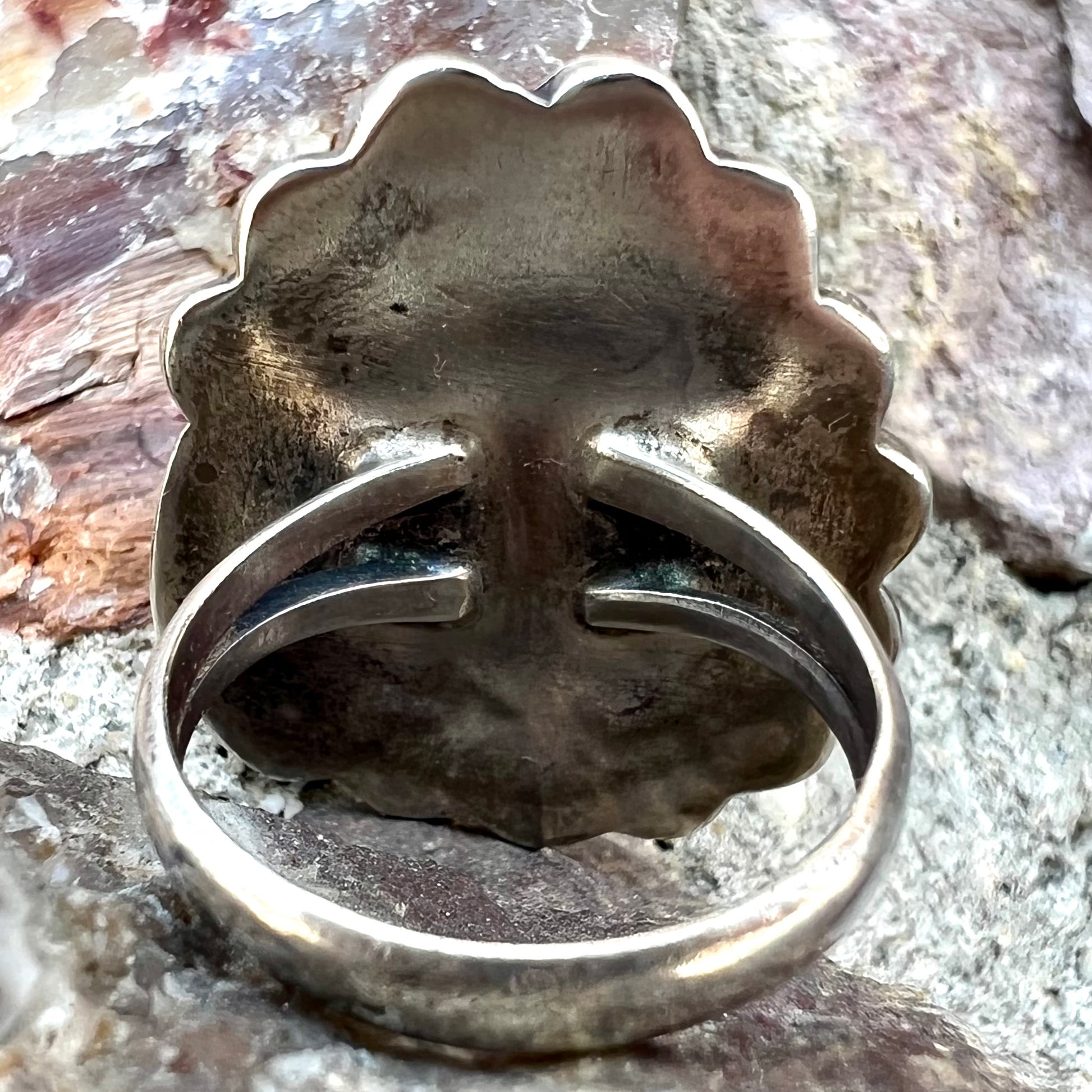 A sterling silver Navajo style ring.  The ring is set with a turquoise stone from Pilot Mountain.  There is a feather decoration next to the stone.