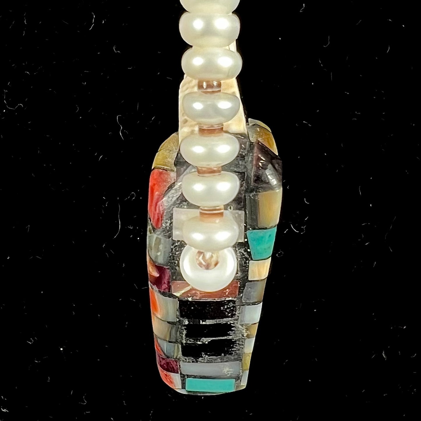 A seashell necklace that has been inlaid with spiny oyster and mother of pearl shell on a pearl bead necklace by Charlene Reano.