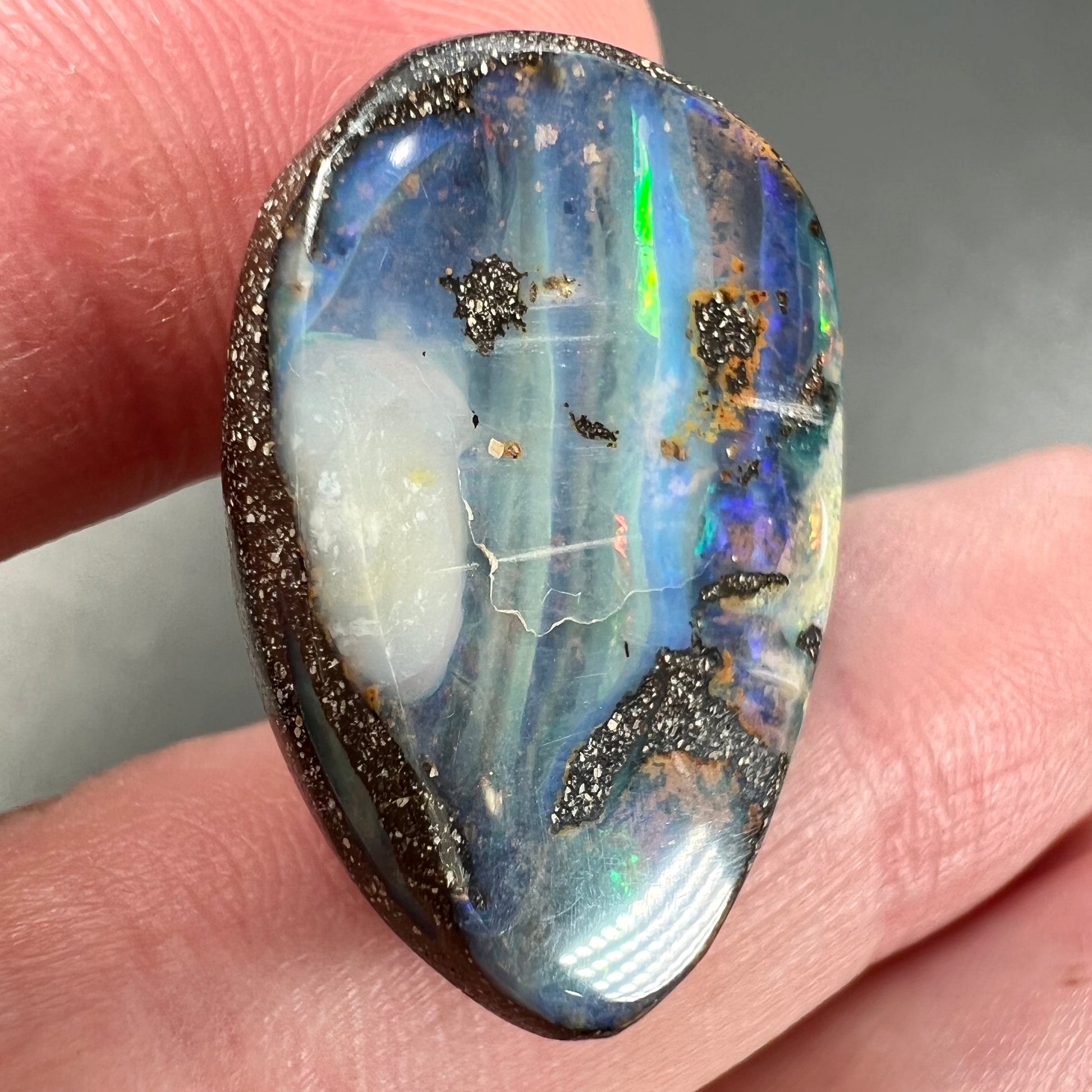 A loose, pear shaped Australian boulder opal.  The pattern on the opal resembles the face of a very sad man.
