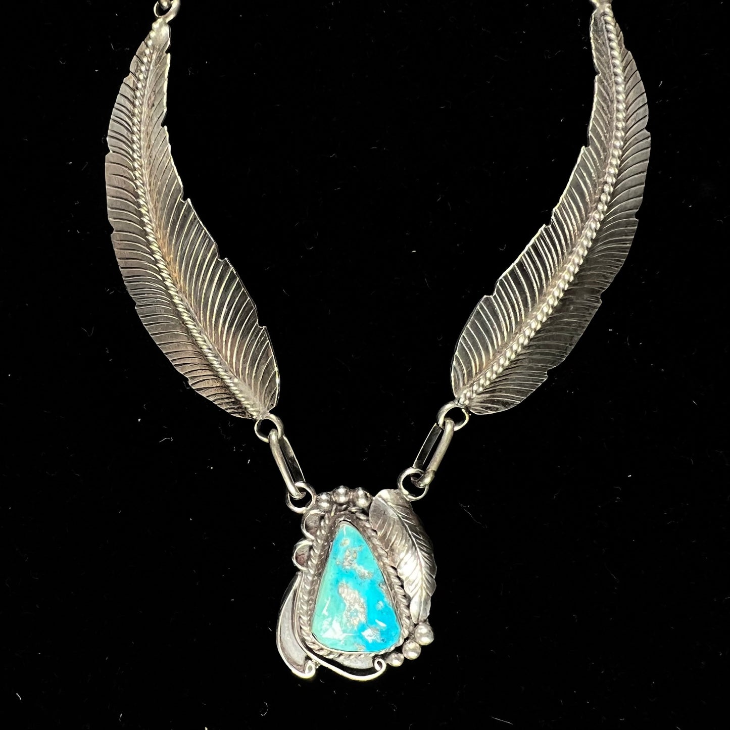 A sterling silver feather motif necklace set with a Sleeping Beauty turquoise stone, handmade by Navajo artist, Jameson Lee.