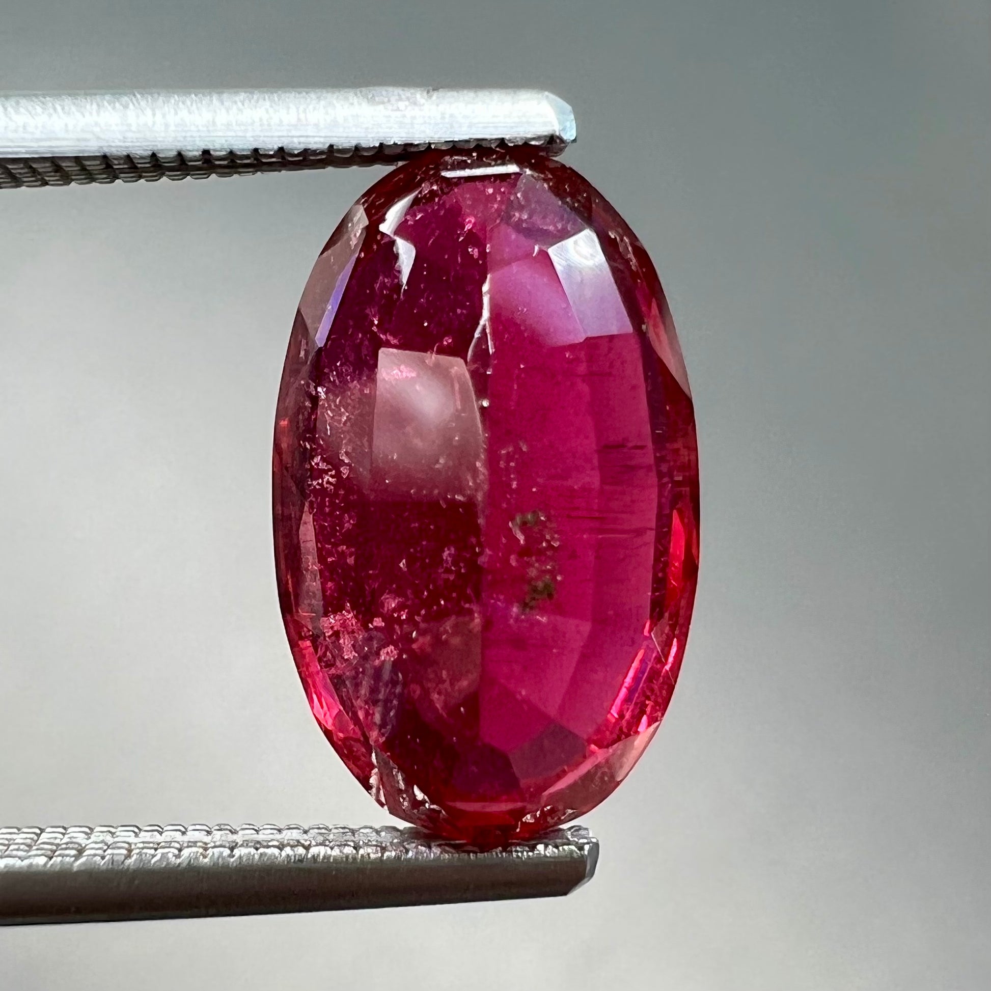 A loose, oval cut, purplish red rubellite tourmaline stone.