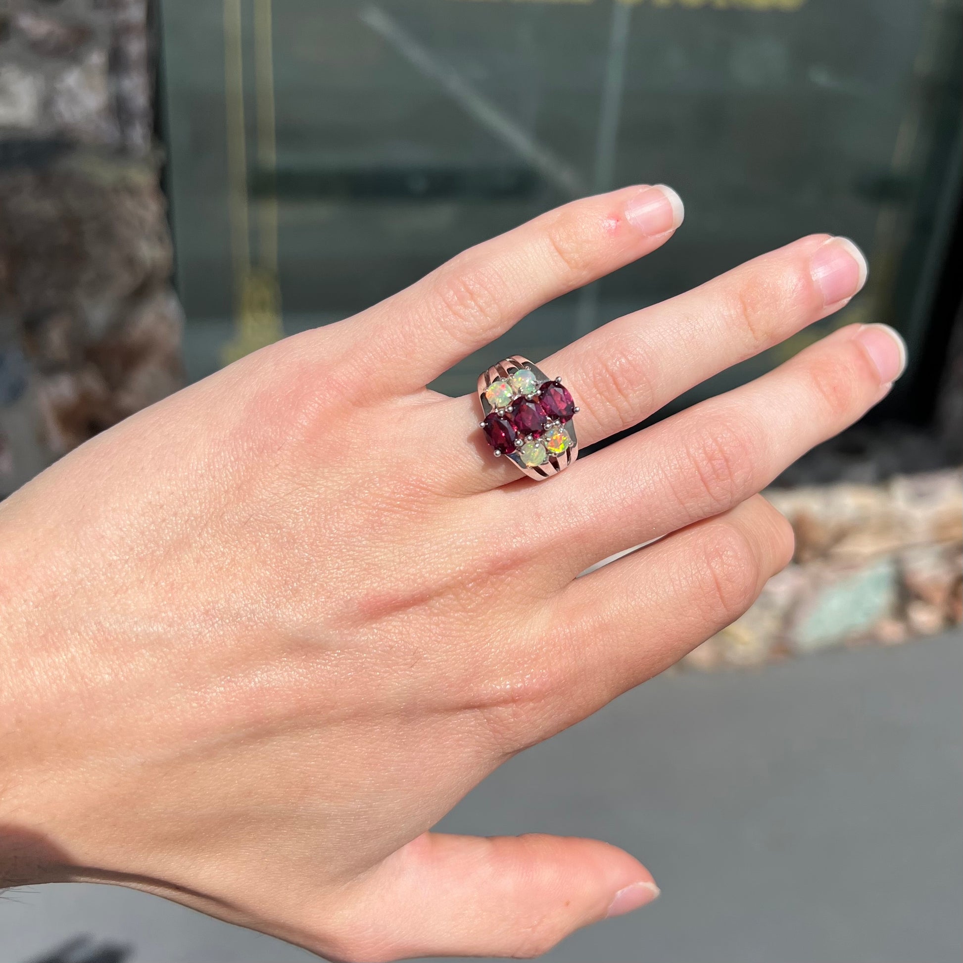 A sterling silver ring set with three oval cut rhodolite garnets and four round cabochon cut Ethiopian opals.