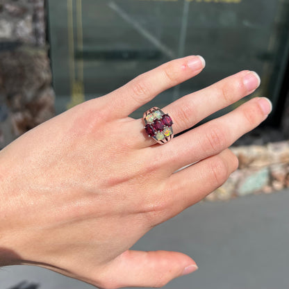 A sterling silver ring set with three oval cut rhodolite garnets and four round cabochon cut Ethiopian opals.
