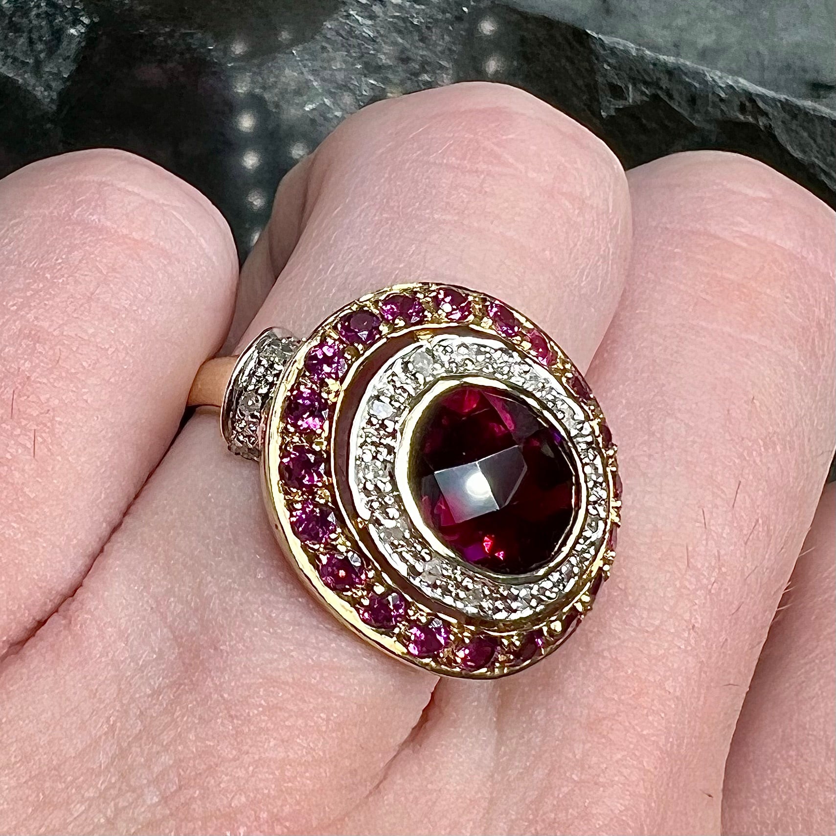 A yellow gold garnet and diamond halo ring set with a checkerboard cut rhodolite garnet center stone.