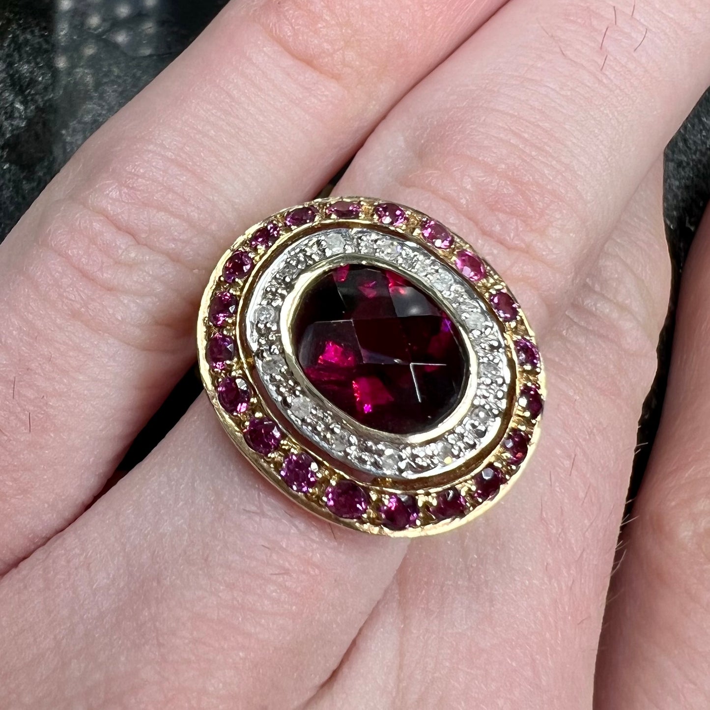 A yellow gold garnet and diamond halo ring set with a checkerboard cut rhodolite garnet center stone.