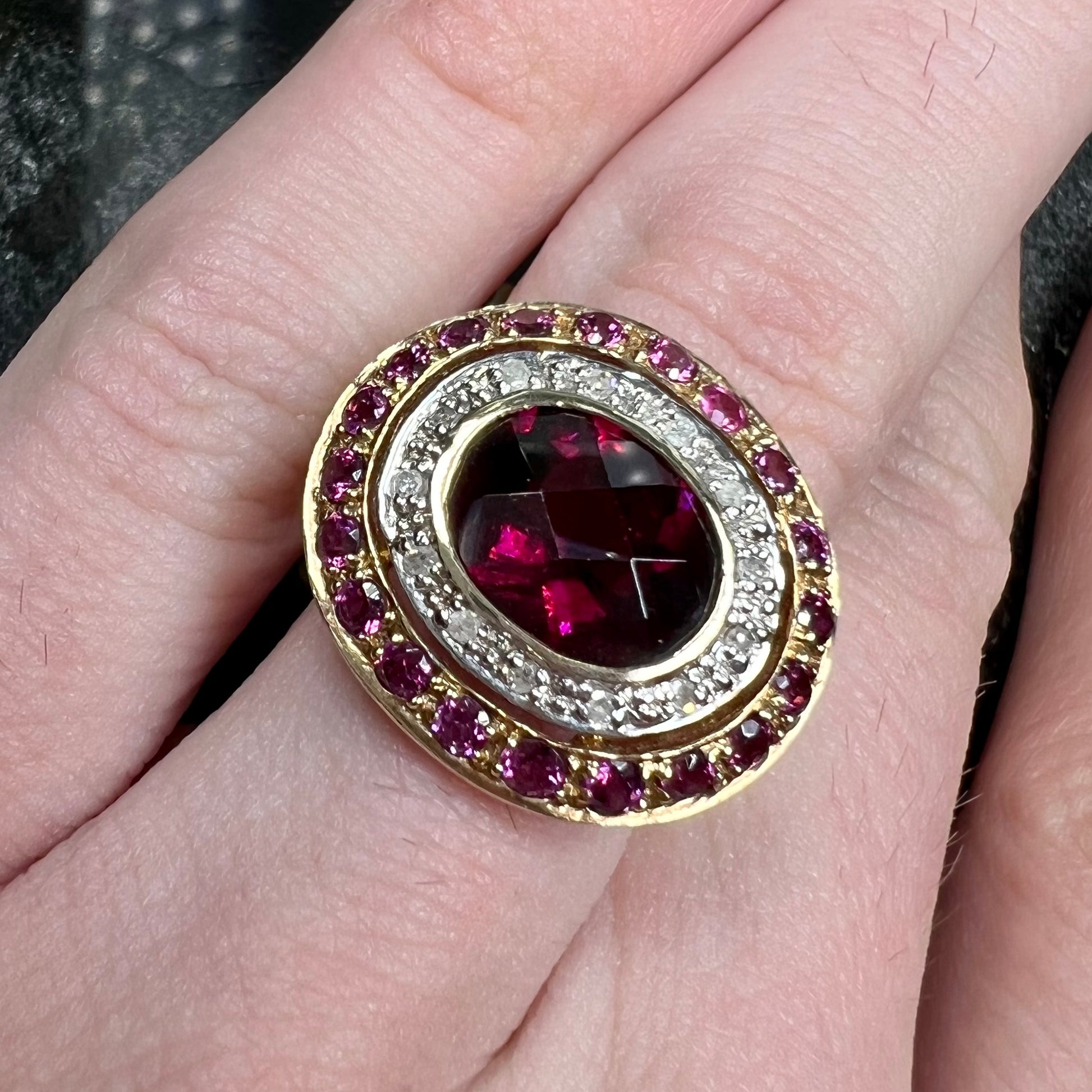 A yellow gold garnet and diamond halo ring set with a checkerboard cut rhodolite garnet center stone.