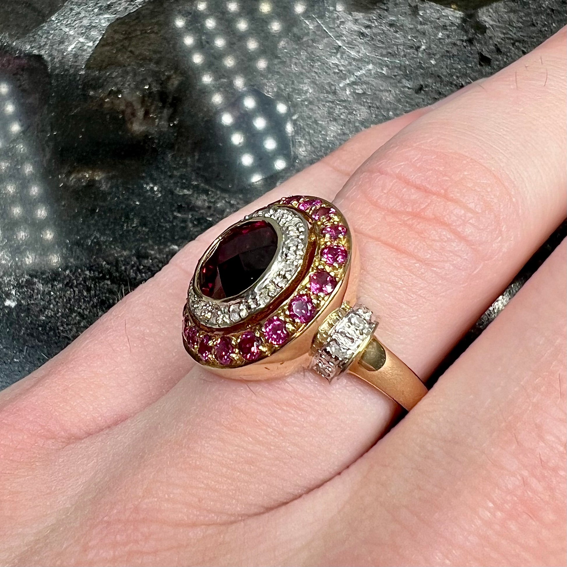 A yellow gold garnet and diamond halo ring set with a checkerboard cut rhodolite garnet center stone.