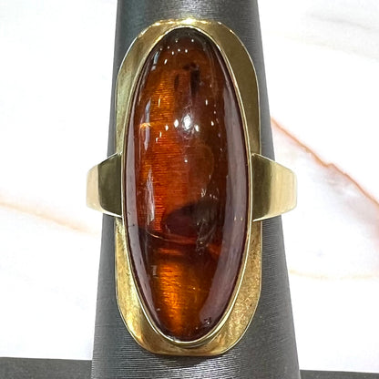 An oval cabochon cut Baltic amber stone set in a yellow gold ring and stamped "AMBER GUILD."