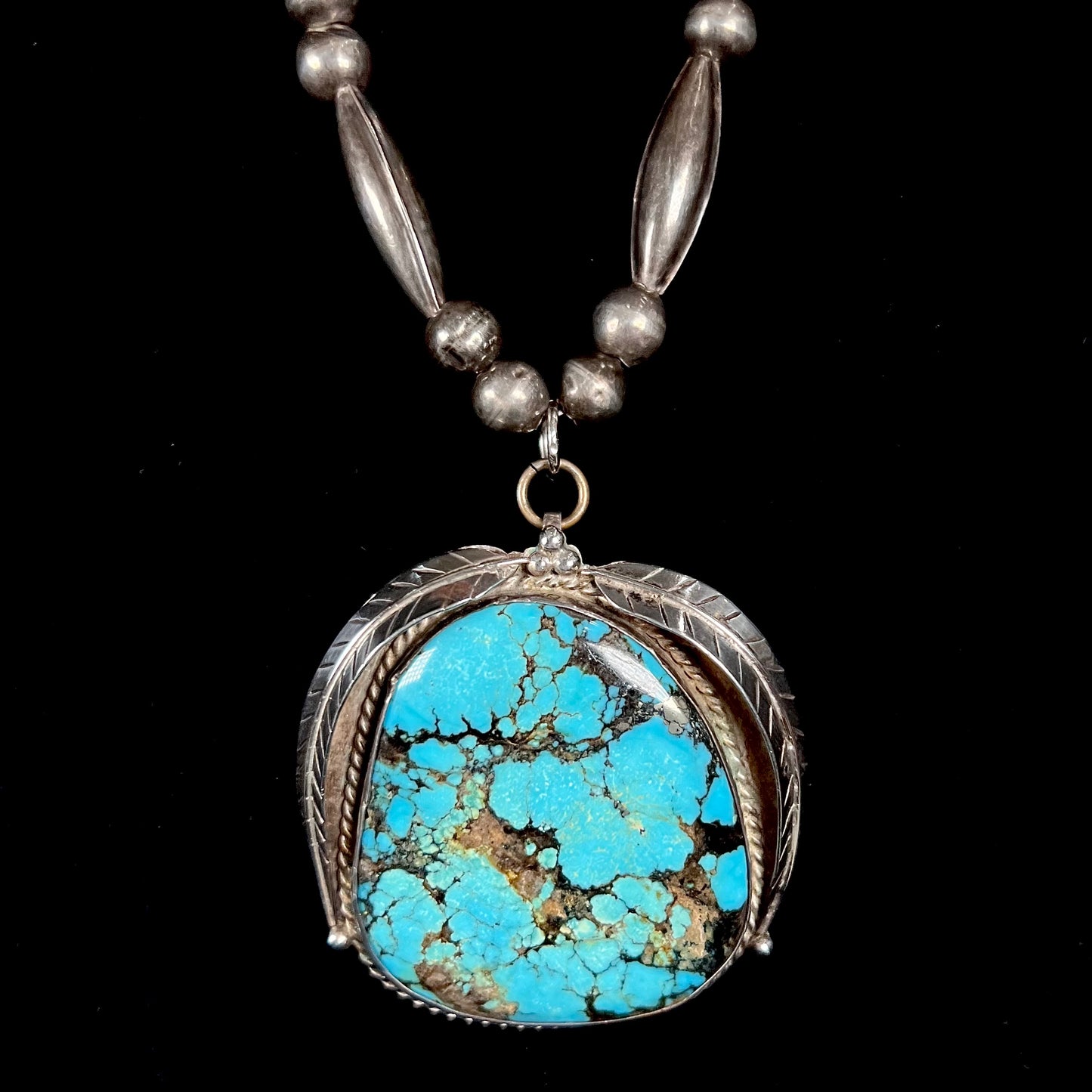 A Navajo style silver beaded necklace set with a Kingman spiderweb turquoise stone.