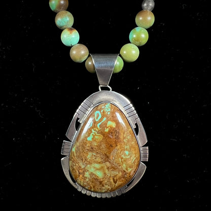 A handmade, likely Navajo silver pendant set with Kingman turquoise on a green Kingman turquoise beaded necklace.