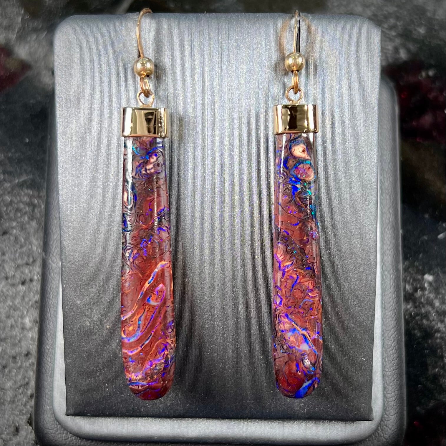 A pair of yellow gold cap Koroit boulder opal dangle earrings.  Purple highlights are seen.