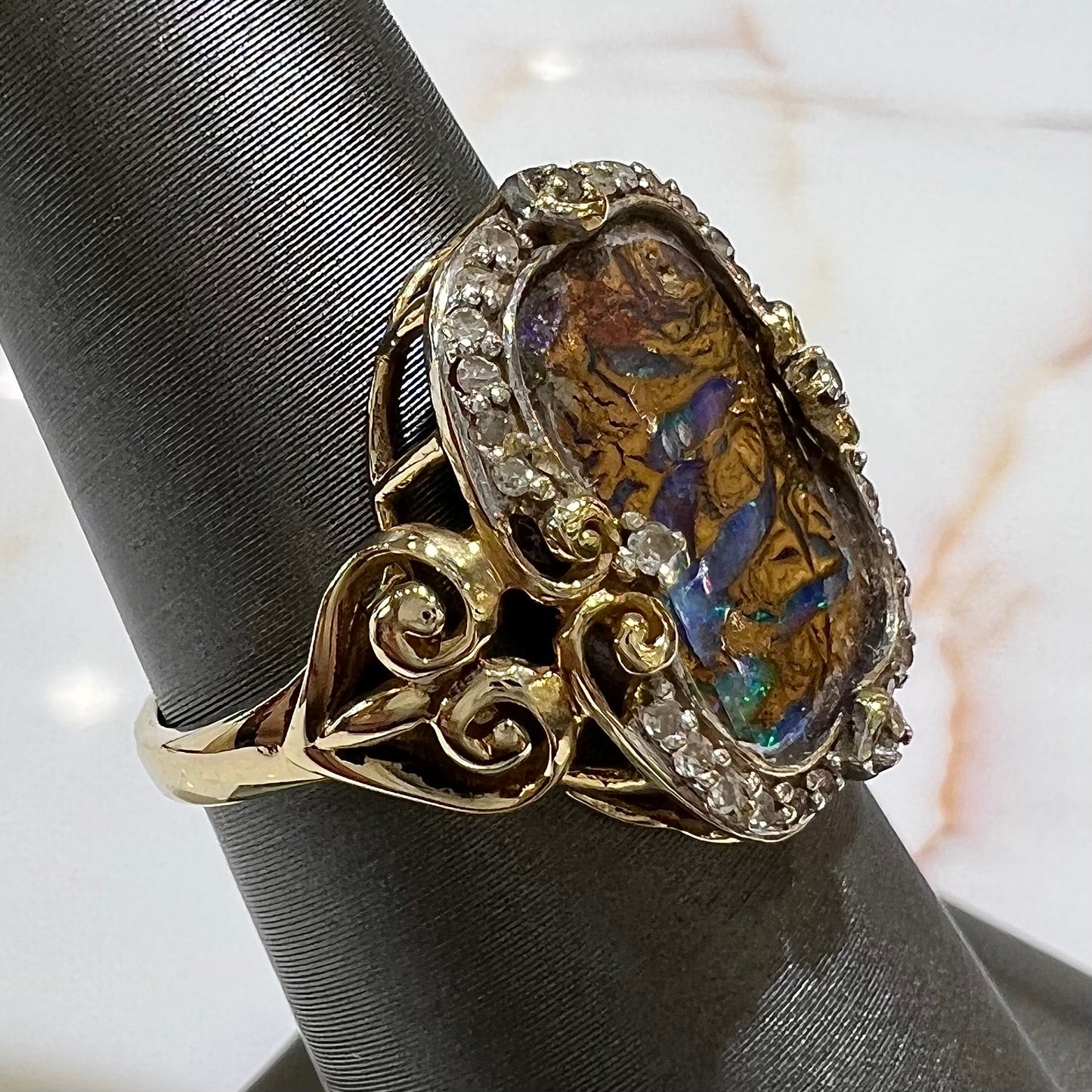 Striped Koroit boulder opal set in a filigree 14k yellow gold setting with diamonds.  The filigree has a heart pattern.