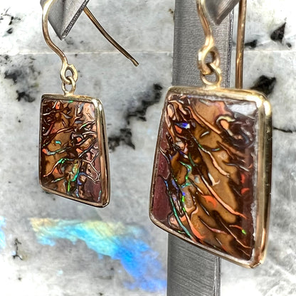 A pair of yellow gold French wire dangle earrings set with Koroit boulder opal.