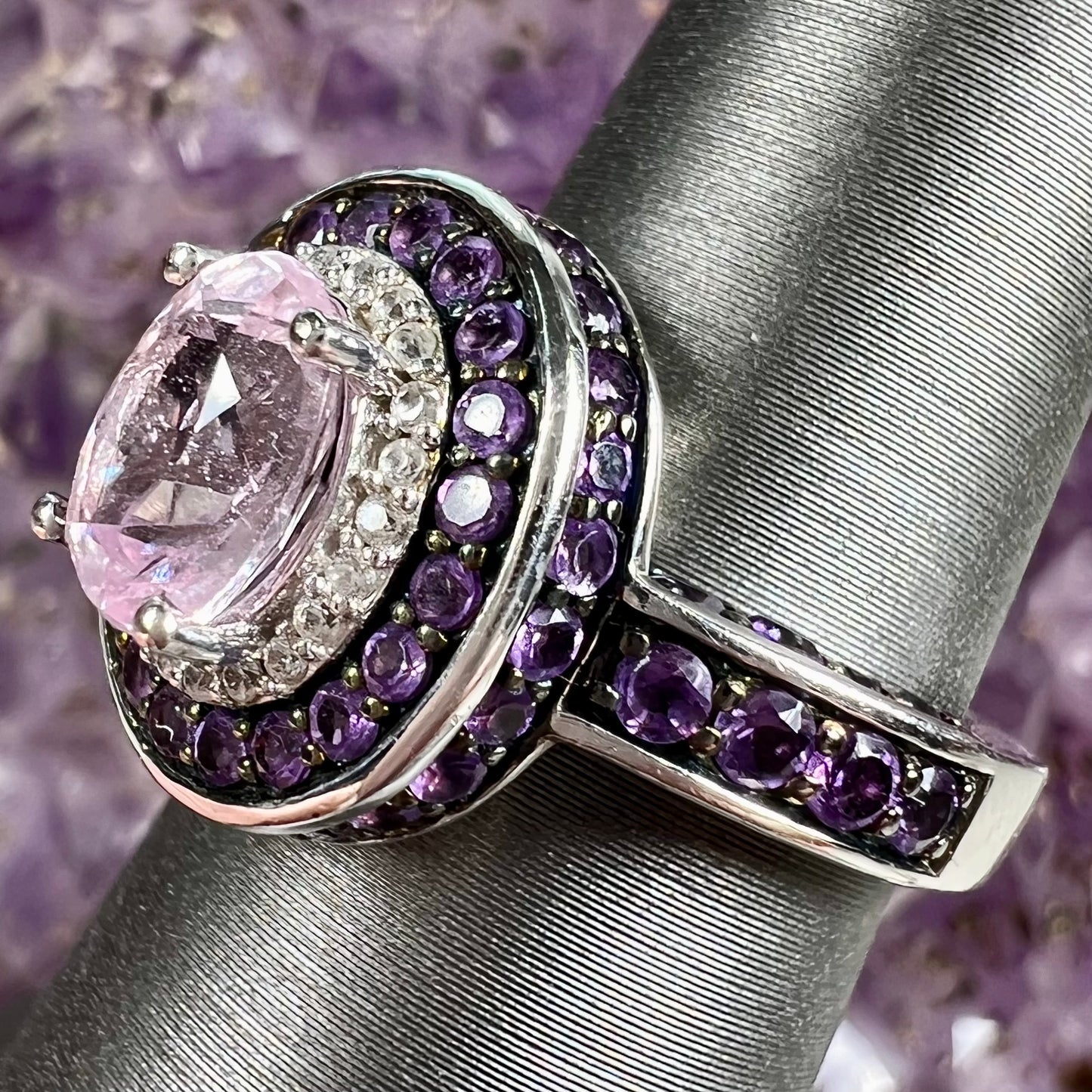A sterling silver oval cut kunzite ring set with a double halo of round cut CZ and amethysts.