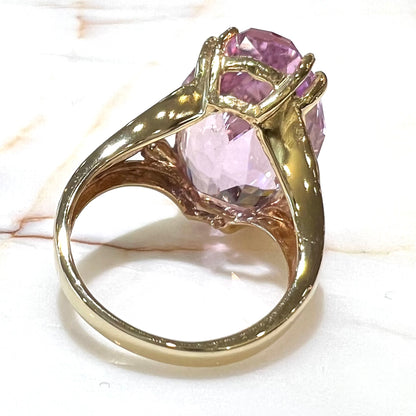 A large, pink kunzite is prong set into a 14kt yellow gold basket-style ring mounting with three diamonds flush set into the design on each side.