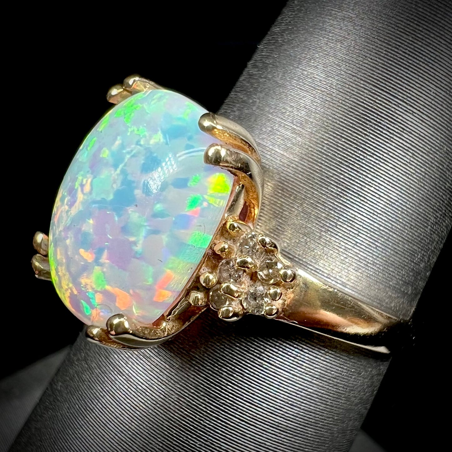 A ladies' yellow gold laboratory created, synthetic, cushion cut opal ring set with natural diamond accents.