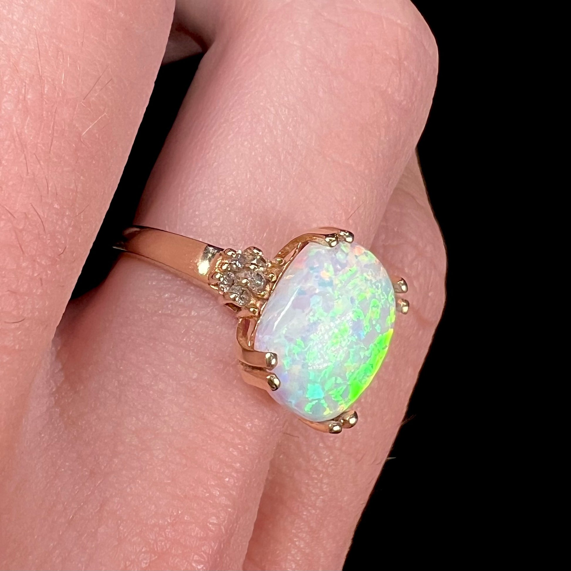 A ladies' yellow gold laboratory created, synthetic, cushion cut opal ring set with natural diamond accents.