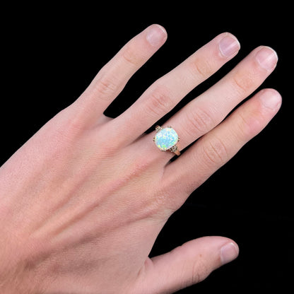 A ladies' yellow gold laboratory created, synthetic, cushion cut opal ring set with natural diamond accents.