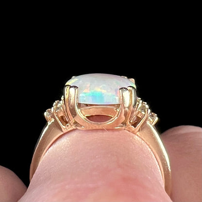 A ladies' yellow gold laboratory created, synthetic, cushion cut opal ring set with natural diamond accents.