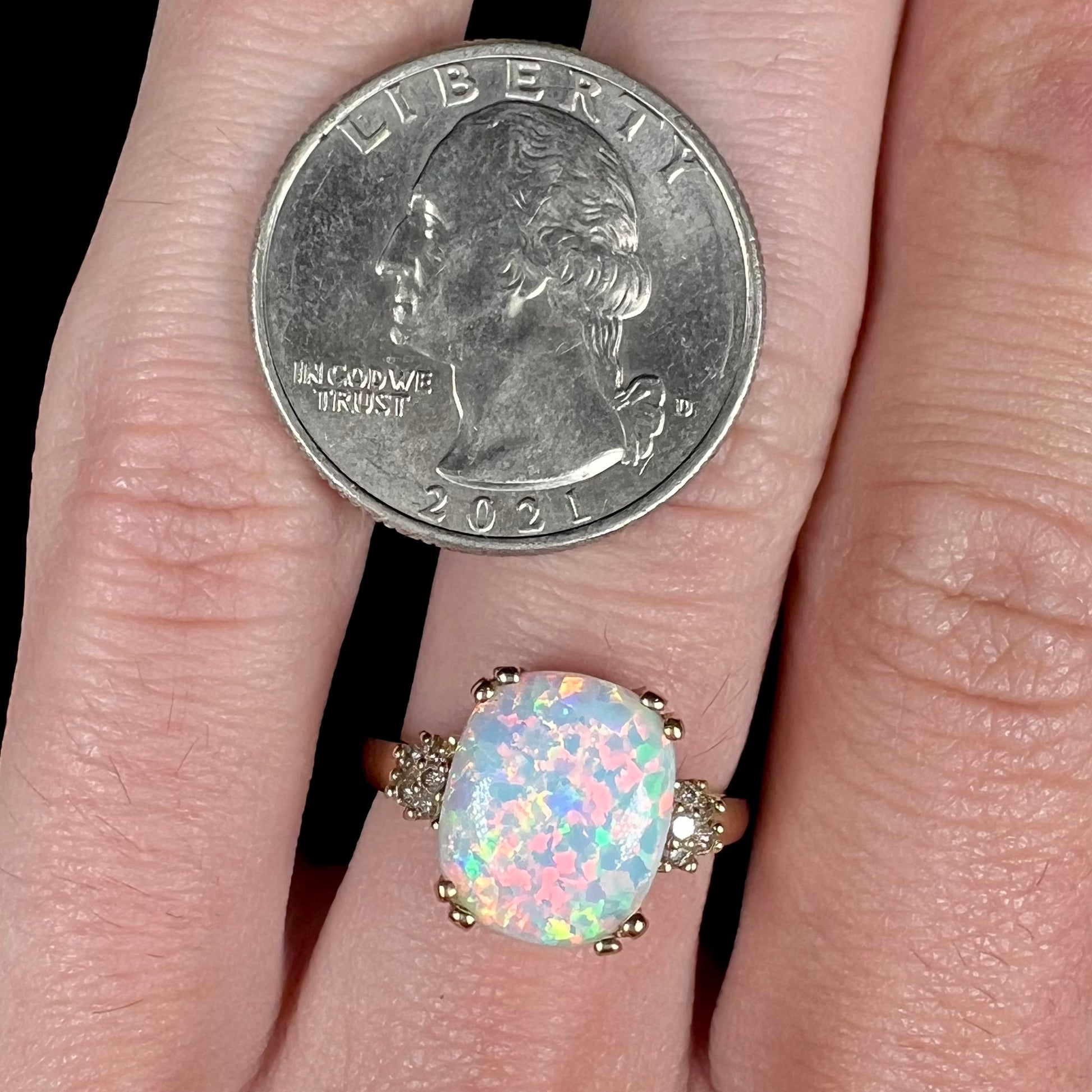 A ladies' yellow gold laboratory created, synthetic, cushion cut opal ring set with natural diamond accents.