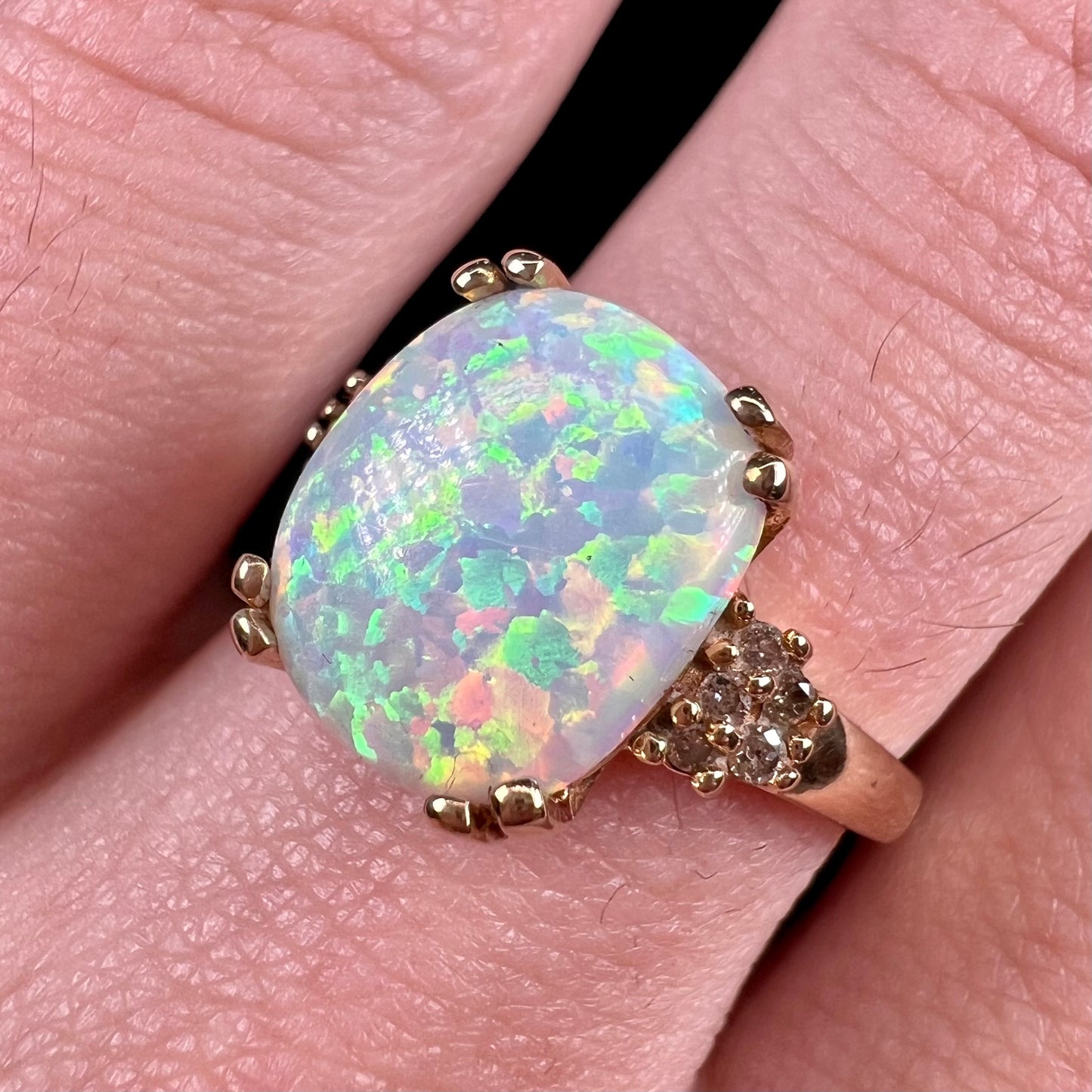 A ladies' yellow gold laboratory created, synthetic, cushion cut opal ring set with natural diamond accents.