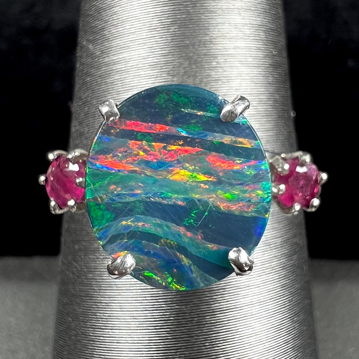 A ladies' 14kt white gold Australian black boulder opal doublet ring set with two round cut rubies.