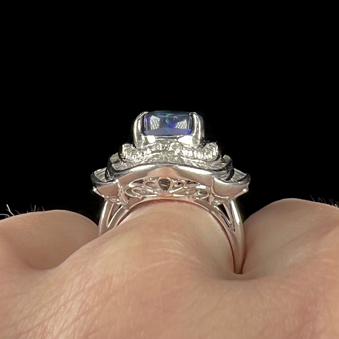 A ladies' platinum diamond halo ring set with a natural black opal stone from Lightning Ridge, Australia.