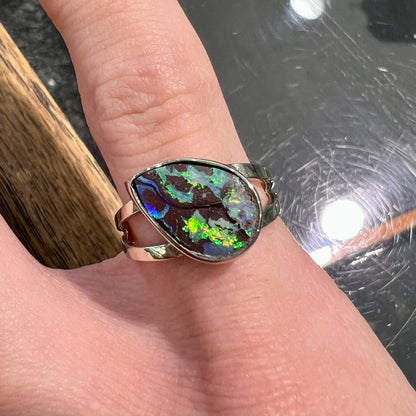 A split shank white gold boulder opal solitaire ring.  The stone has a natural hematite seam that runs through it.