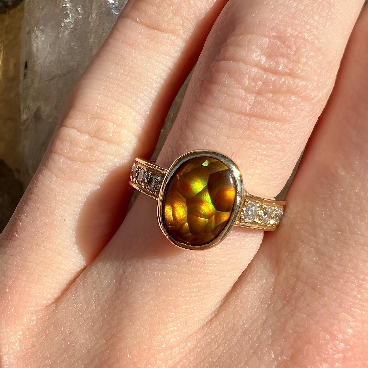 A ladies' oval cabochon cut fire agate and diamond engagement ring cast in yellow gold.