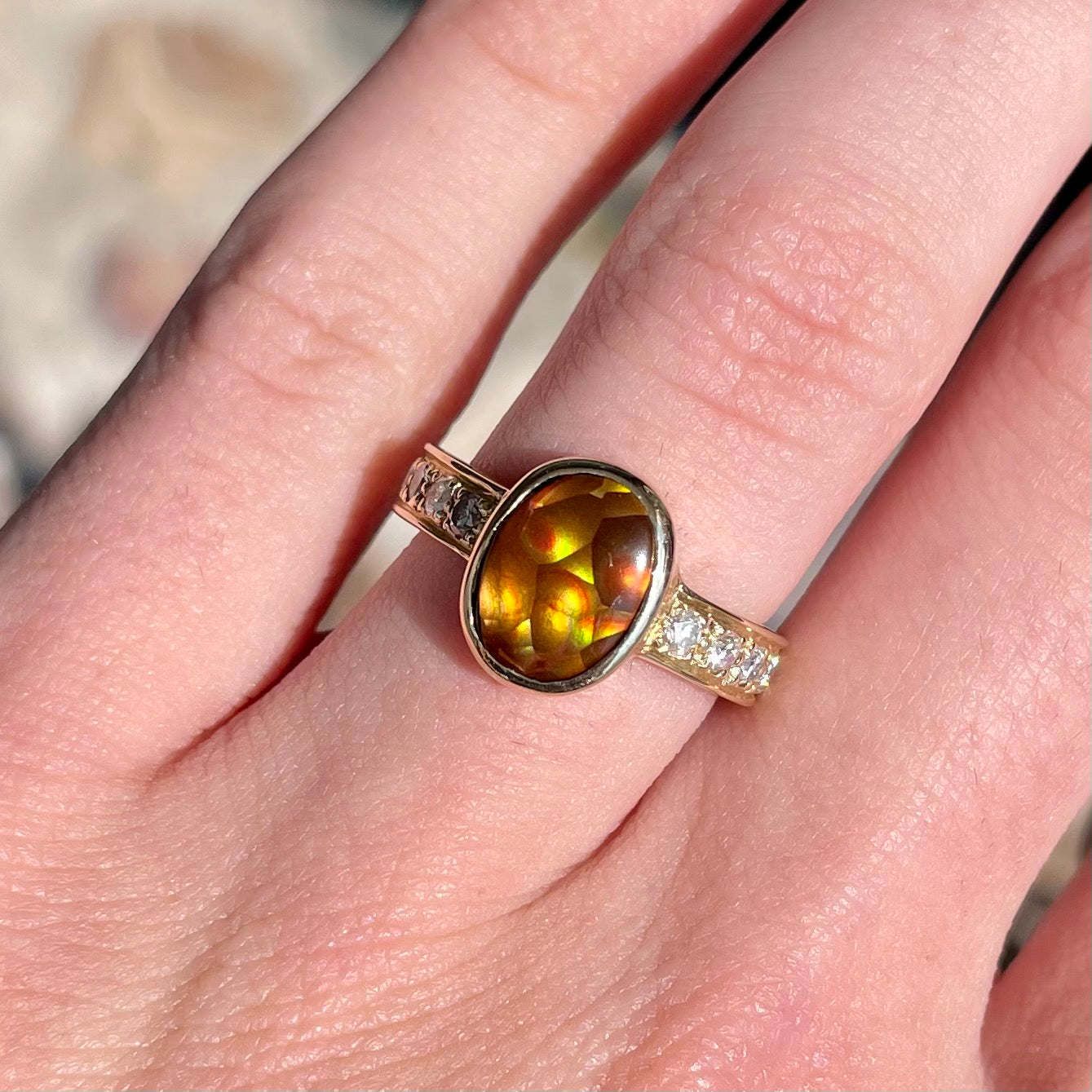 A ladies' oval cabochon cut fire agate and diamond engagement ring cast in yellow gold.
