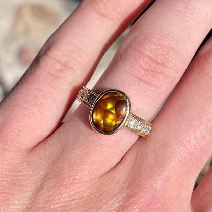 A ladies' oval cabochon cut fire agate and diamond engagement ring cast in yellow gold.