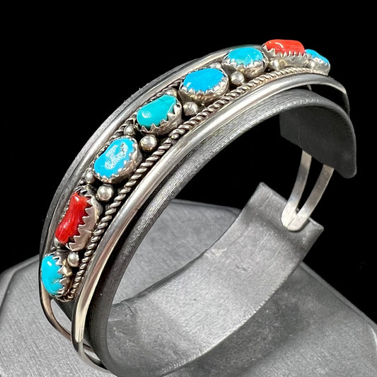 A silver ladies' turquoise and coral cuff bracelet, handmade by Navajo artist, John Delvin.