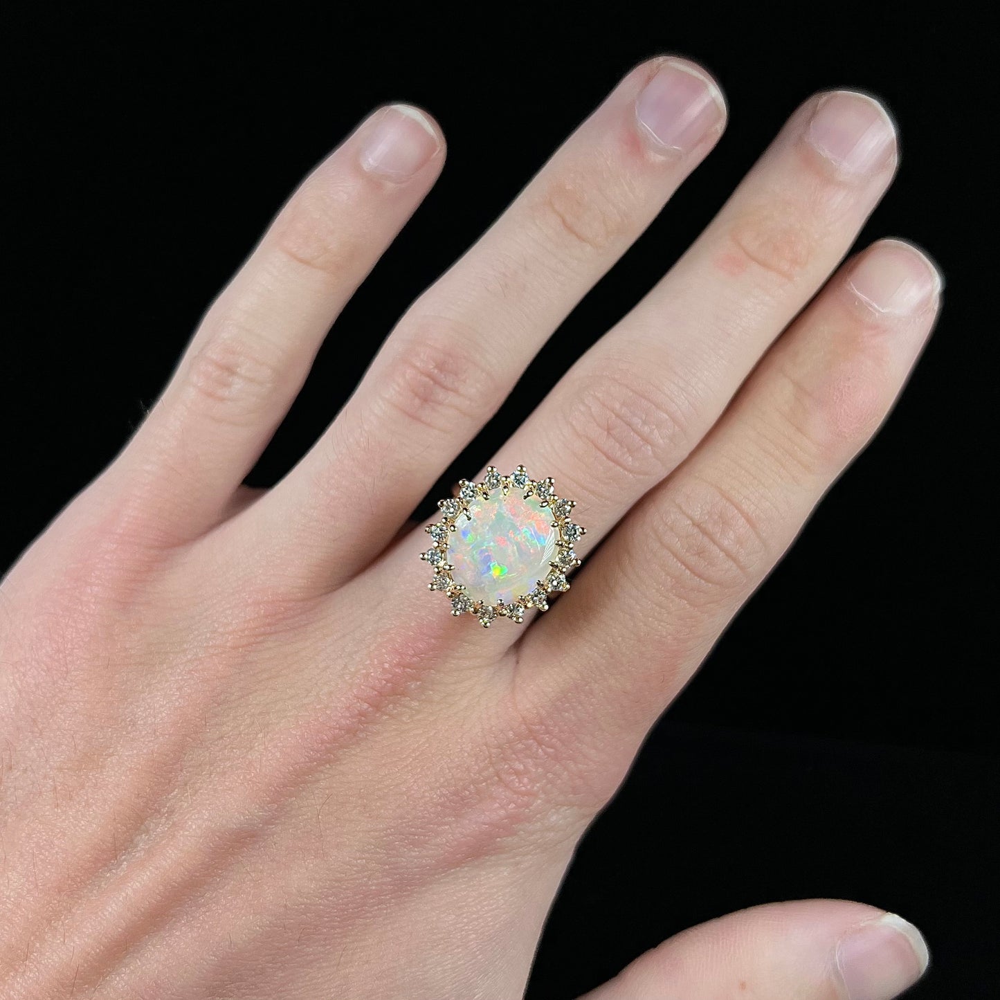 A ladies' diamond halo ring set with a Coober Pedy opalized seashell in yellow gold.