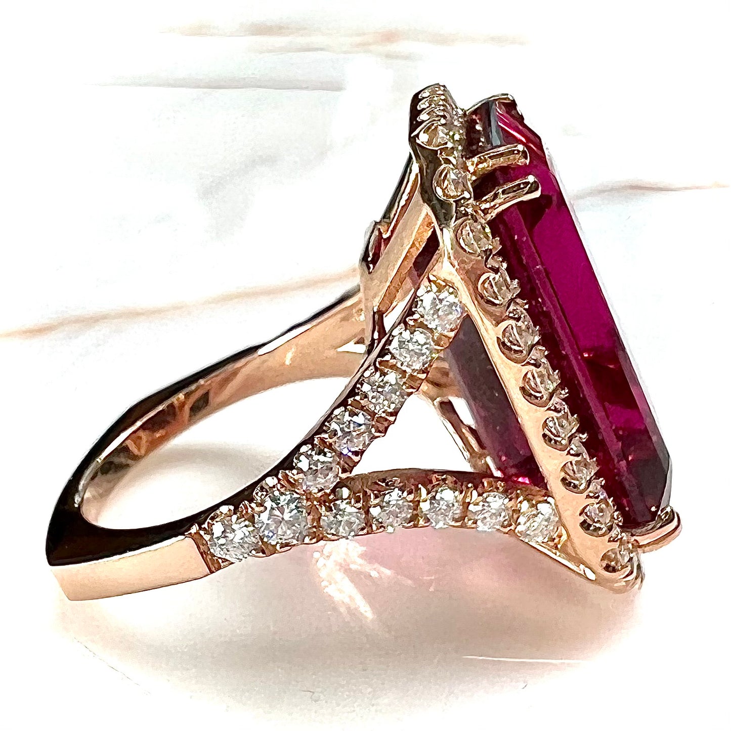 Red emerald cut rubellite tourmaline gemstone set with near flawless round cut diamonds in rose gold.