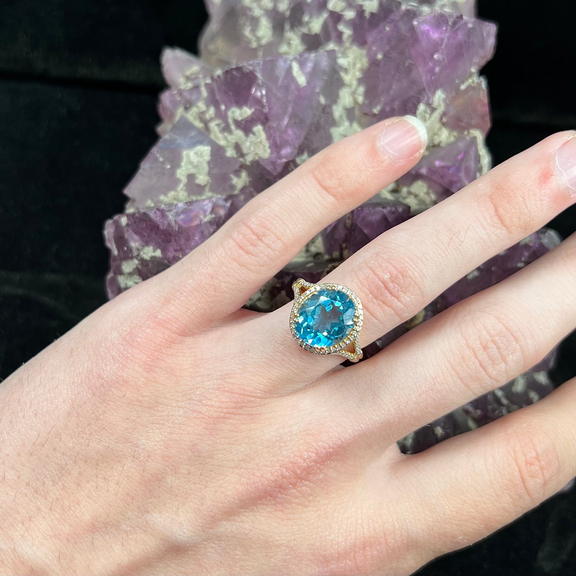 An oval cut Swiss blue topaz and diamond pave split shank ring in yellow gold.