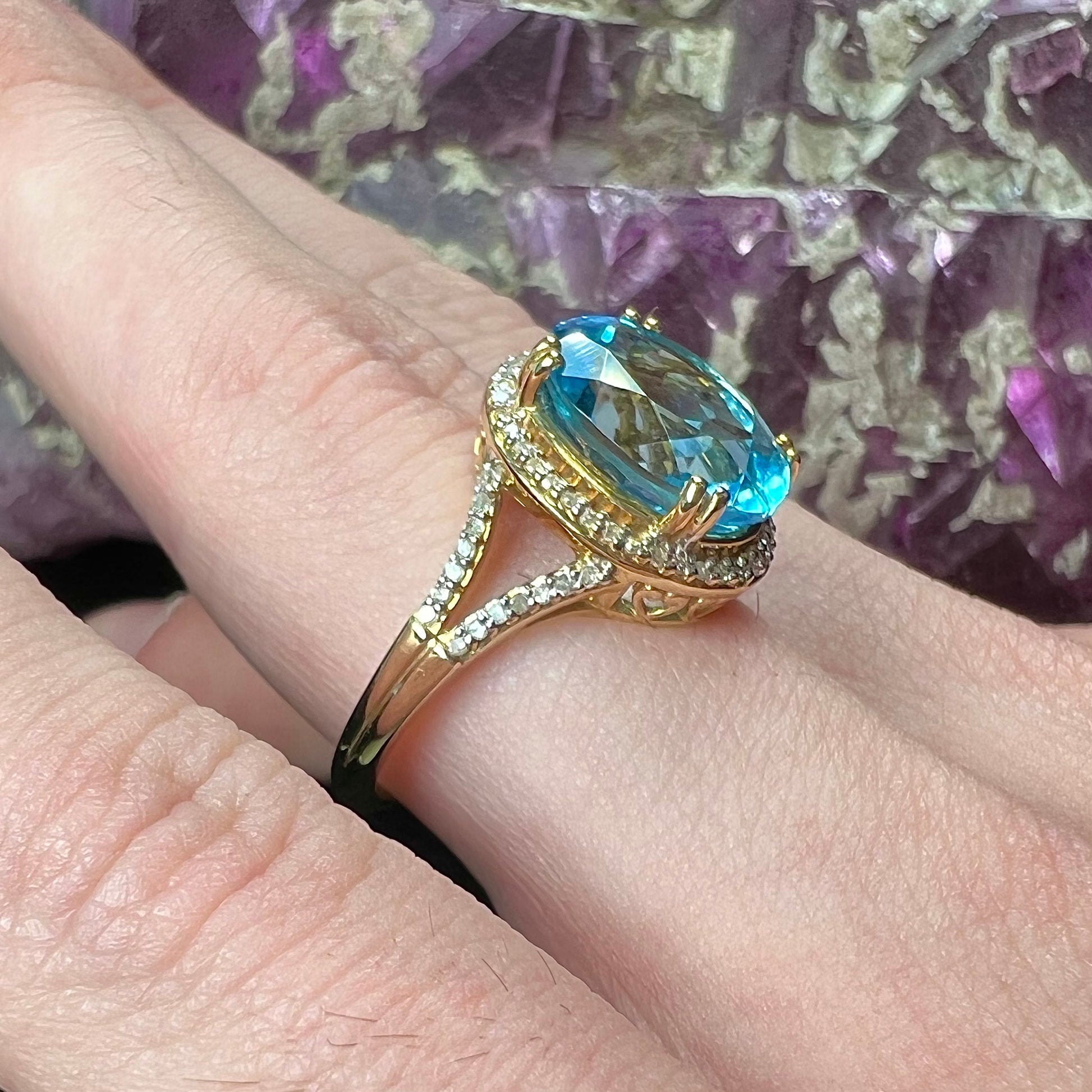 An oval cut Swiss blue topaz and diamond pave split shank ring in yellow gold.