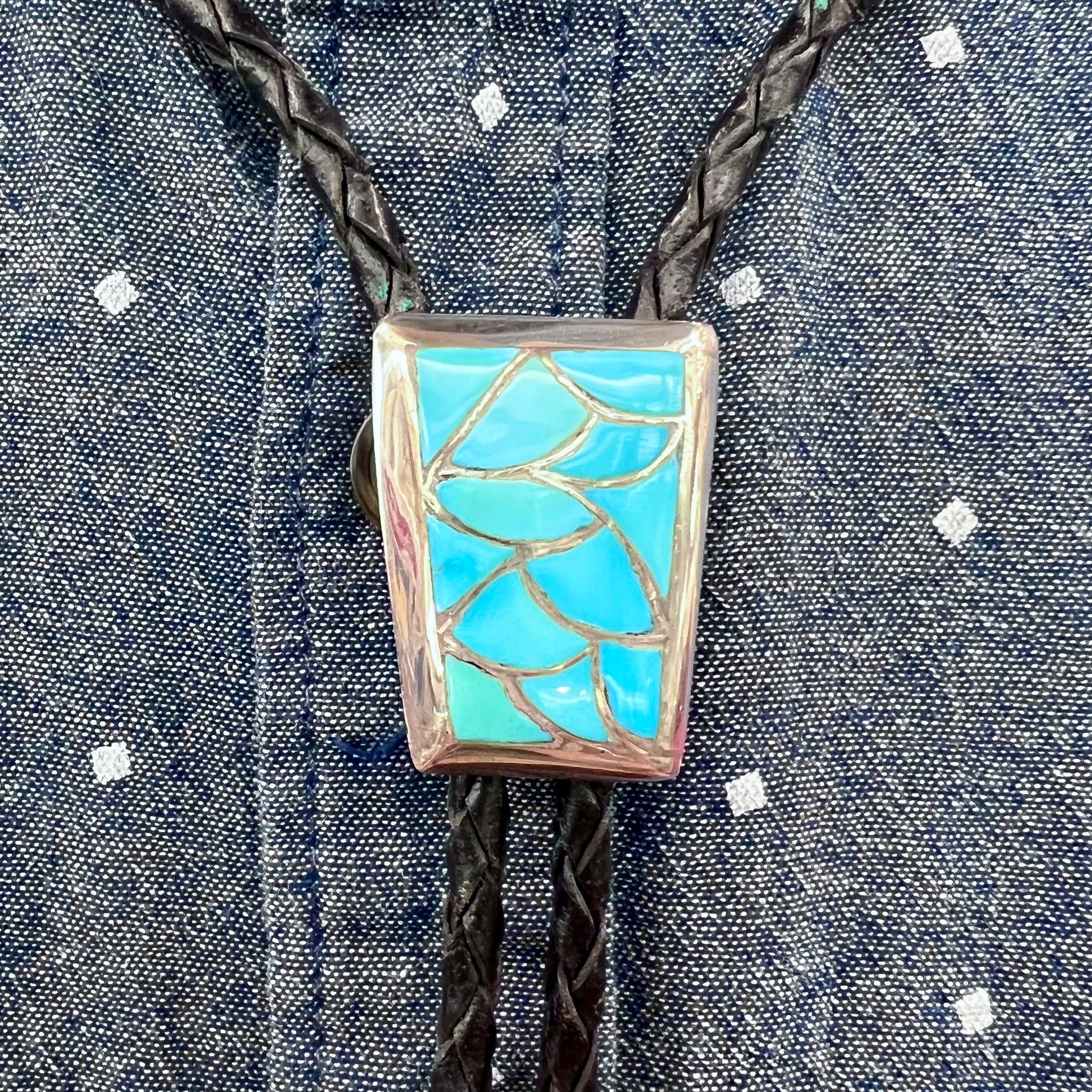 A silver turquoise inlay bolo tie handmade by Navajo artist, Lillian Fernando.