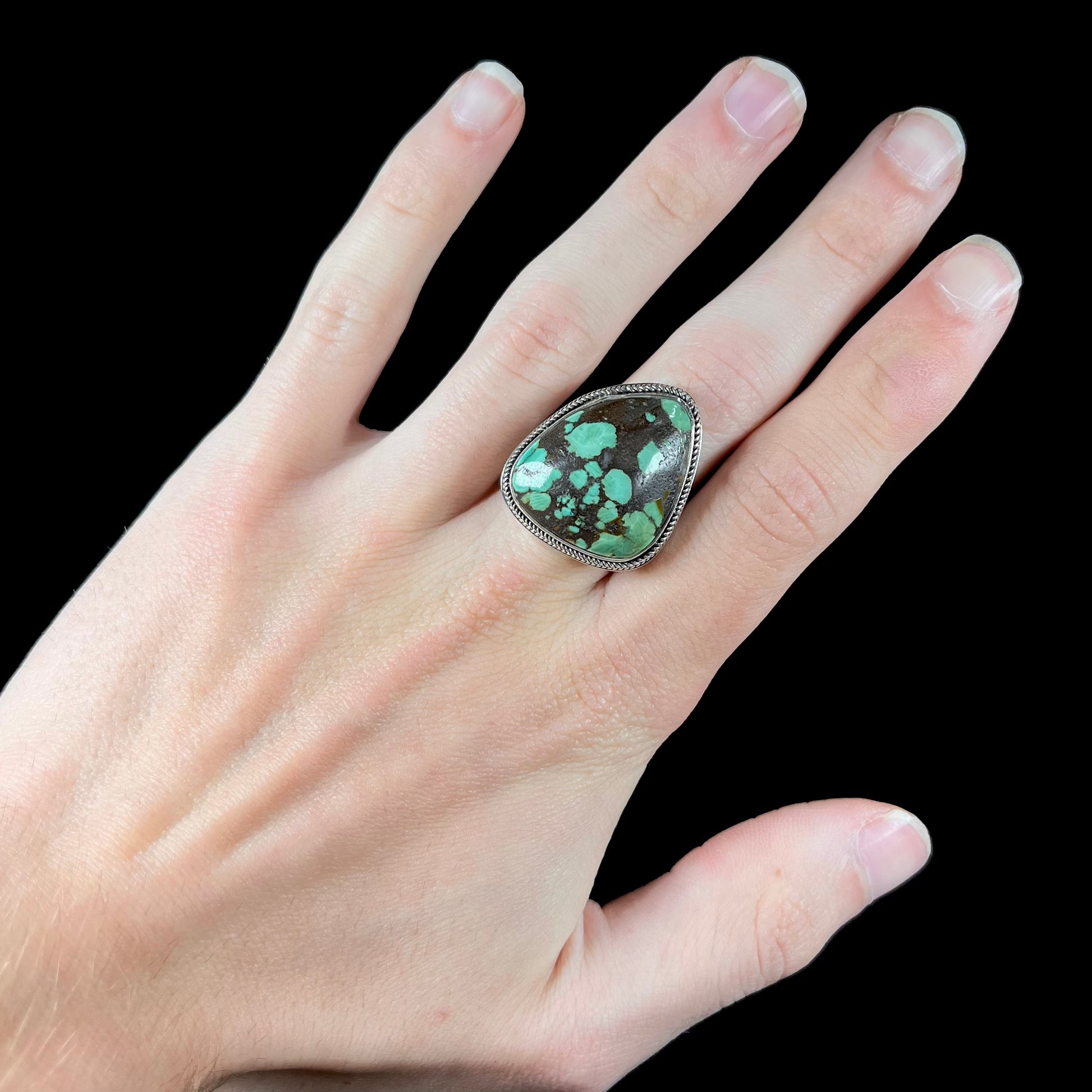 A sterling silver ring bezel set with a green spotted turquoise stone from Carico Lake, Nevada.