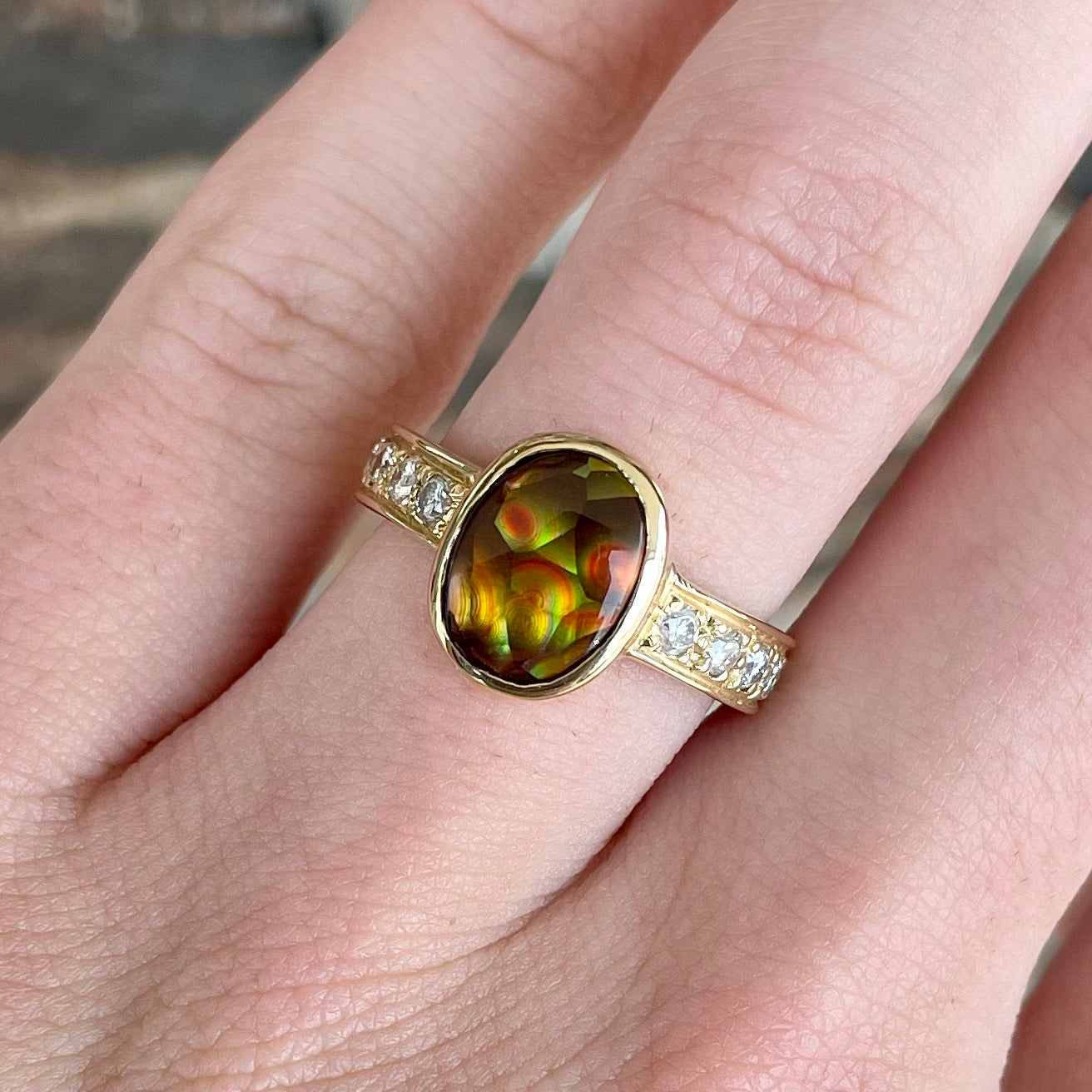A ladies' oval cabochon cut fire agate and diamond engagement ring cast in yellow gold.