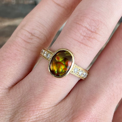 A ladies' oval cabochon cut fire agate and diamond engagement ring cast in yellow gold.