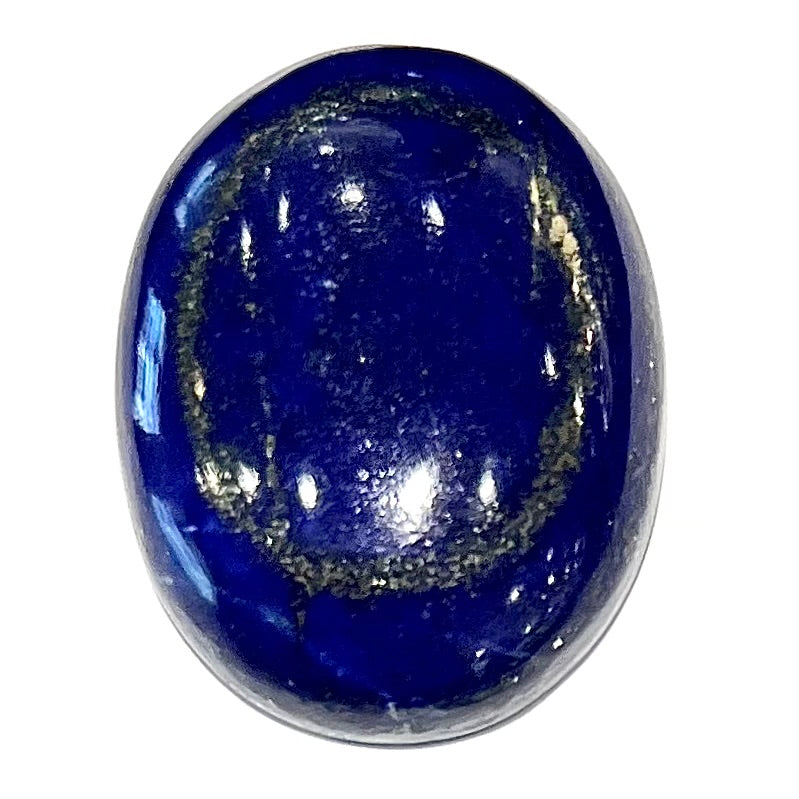 A loose, oval cabochon cut lapis lazuli stone.  A circle of pyrite inclusions is seen on the front.