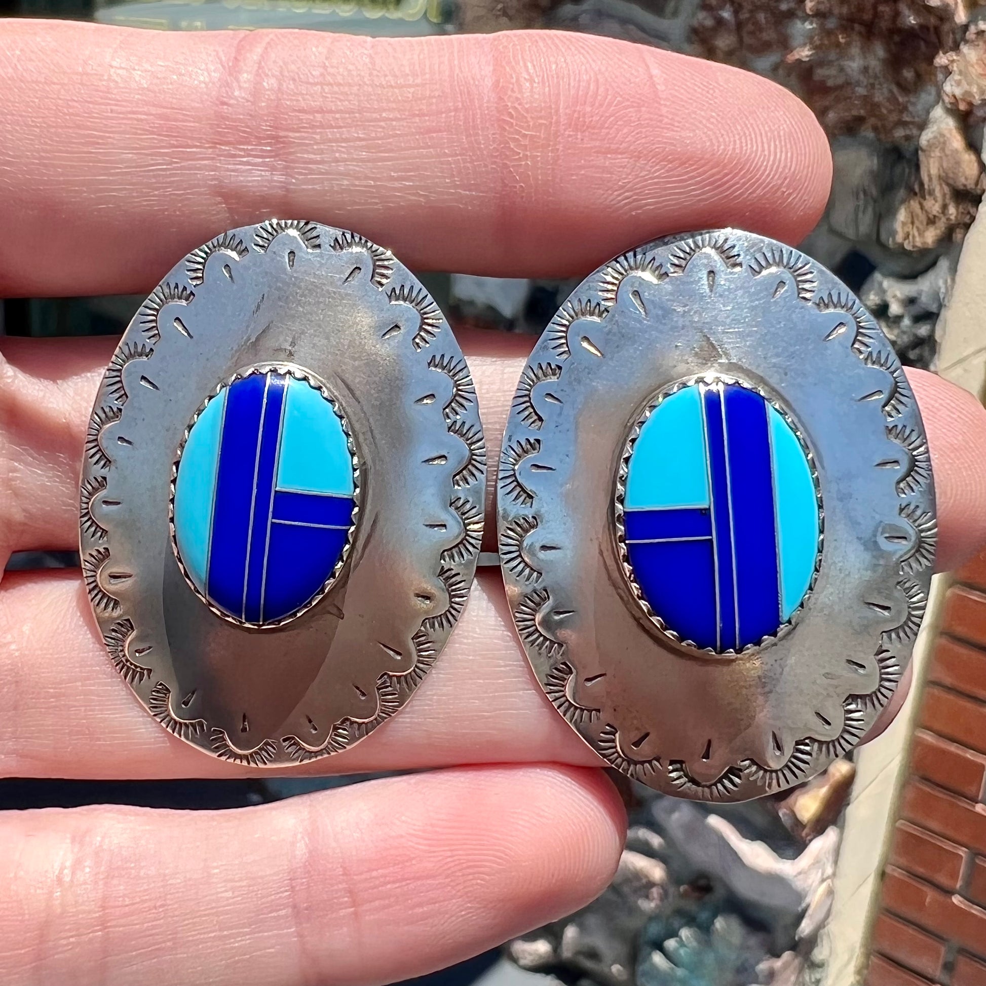 A pair of sterling silver concho earrings set with lapis lazuli and turquoise stone inlay.