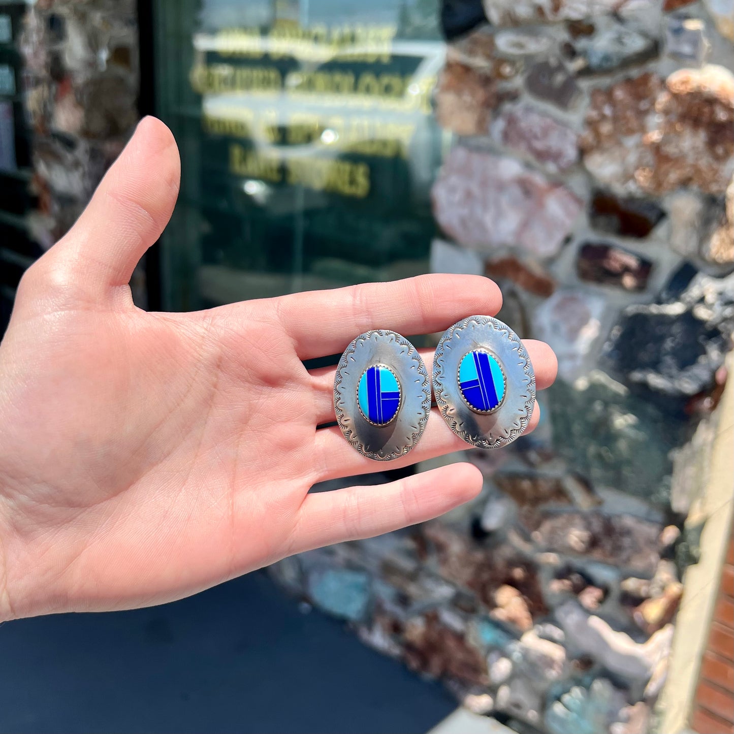 A pair of sterling silver concho earrings set with lapis lazuli and turquoise stone inlay.