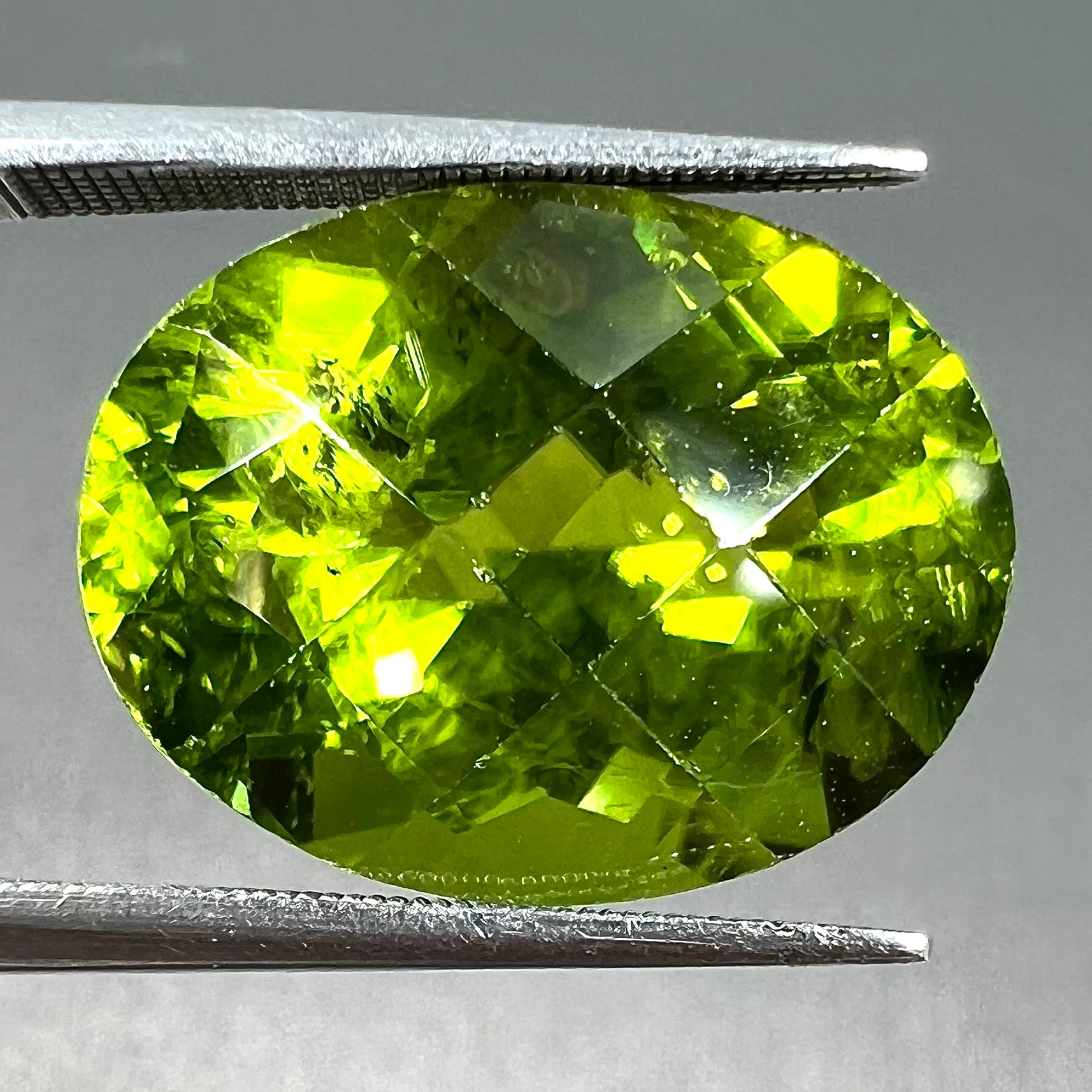 A loose, faceted oval checkerboard cut peridot gemstone from Pakistan.