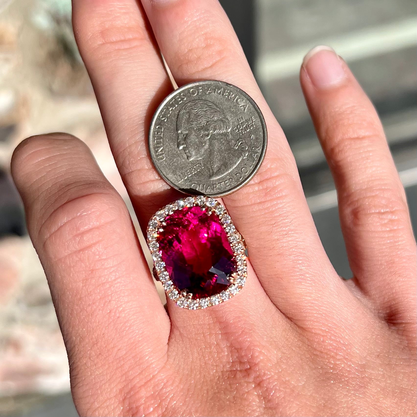 A rose gold, split shank engagement ring set with a cushion cut rubellite tourmaline in a diamond halo.