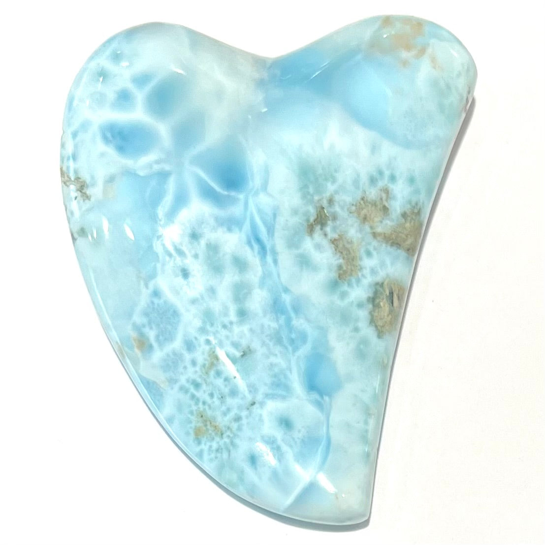 A loose larimar stone that has been hand-carved in the shape of a freeform heart.