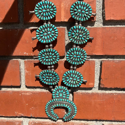 A Native American silver squash blossom turquoise petit point set with turquoise by Larry Moses Begay.