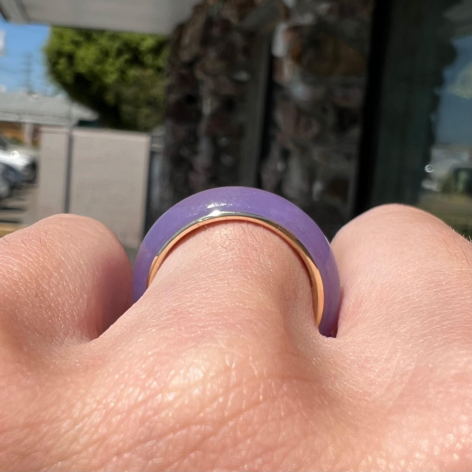 A stone ring carved from purple jadeite jade and mounted on a gold band.