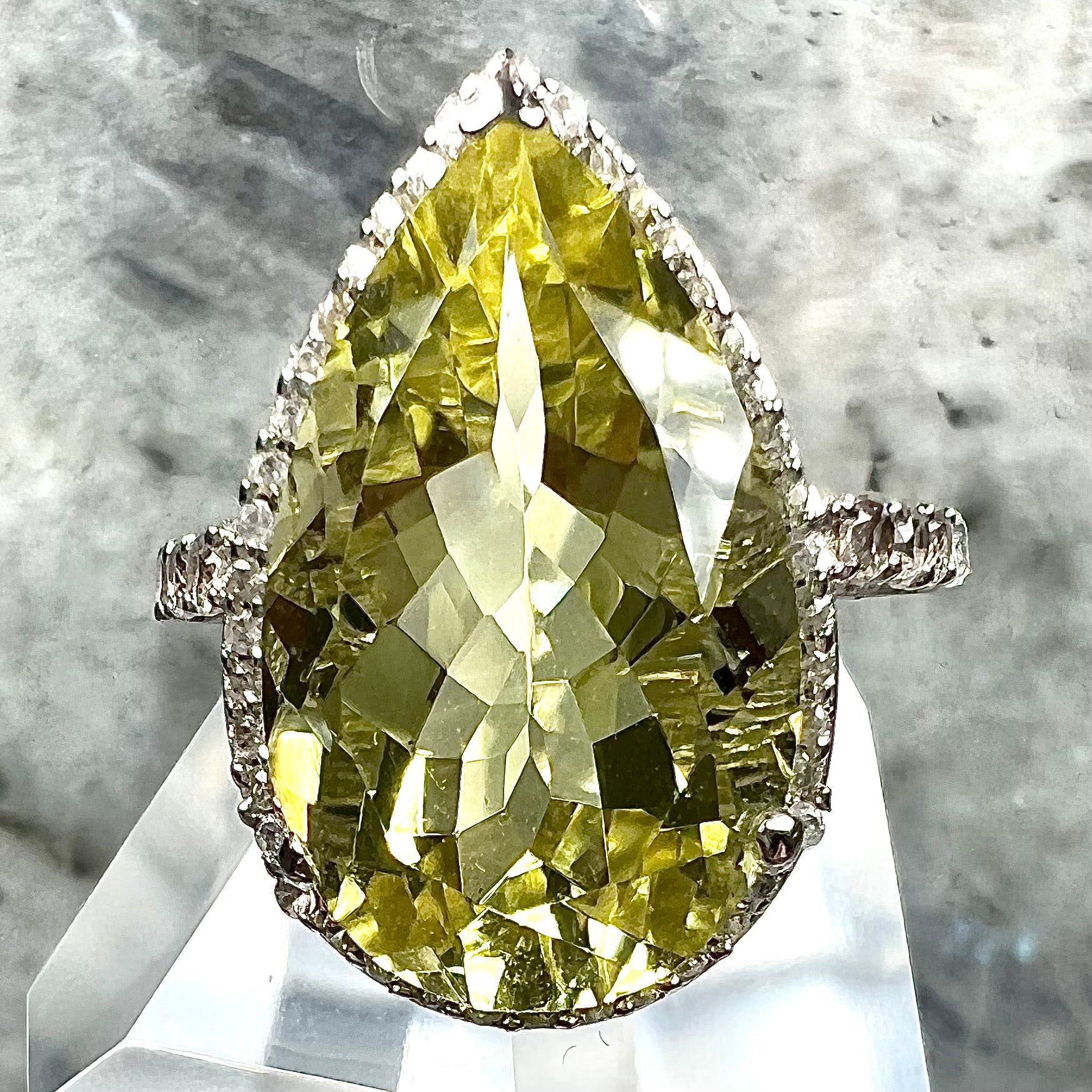 A pear shape lemon quartz set in a sterling silver and white topaz halo ring.