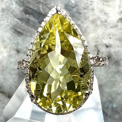A pear shape lemon quartz set in a sterling silver and white topaz halo ring.